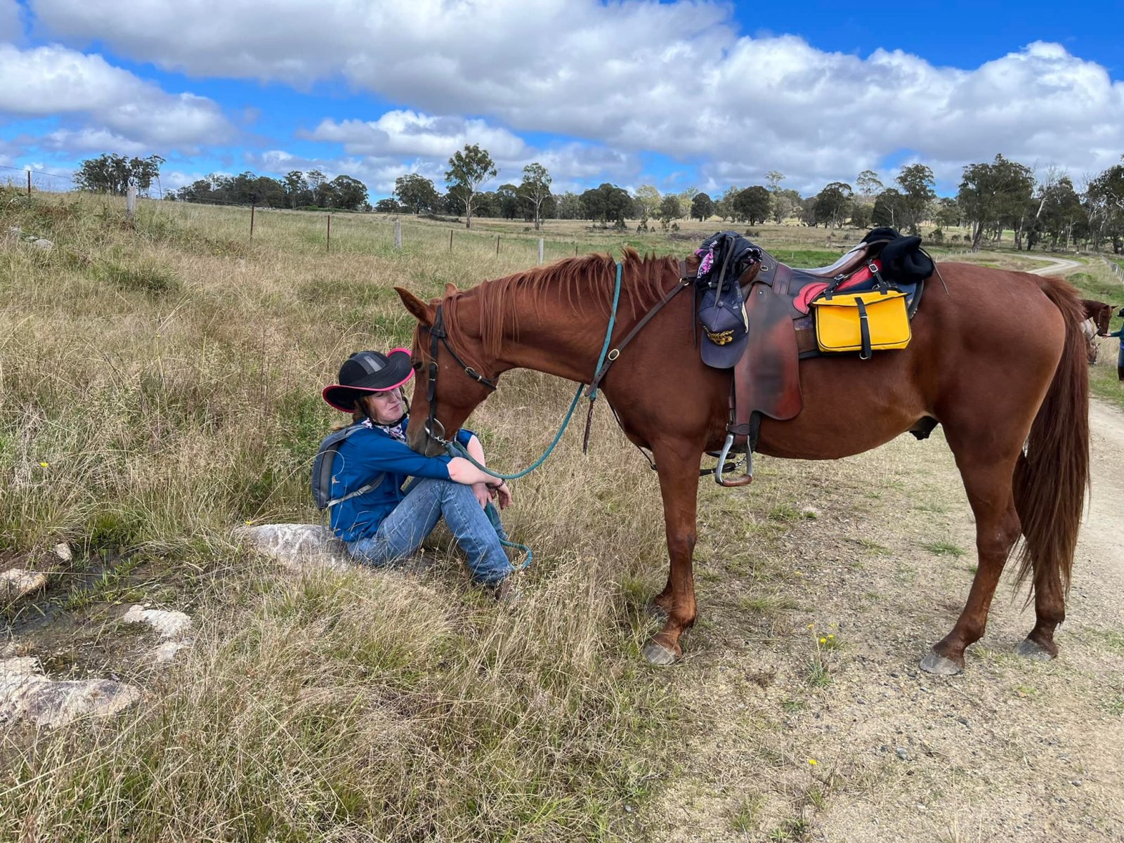 a woman resting with her horse on a field