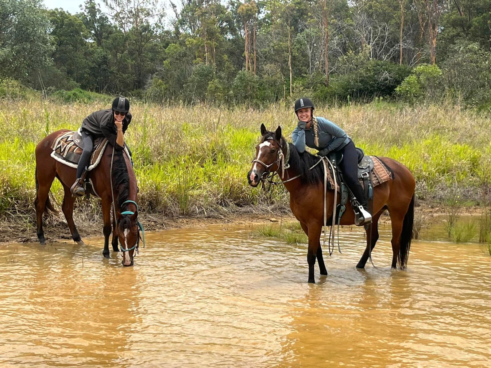 two women and their horses resting on a river