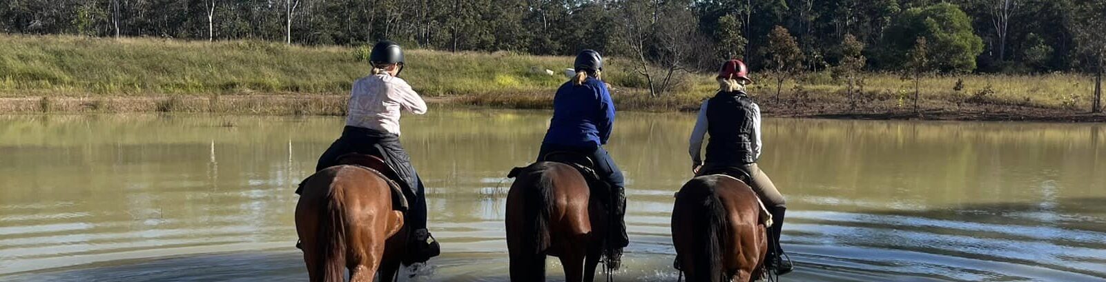 a group of girls riding horses on a river