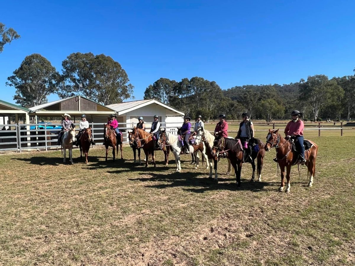 a group of people on horses posing for the camera in front of a building