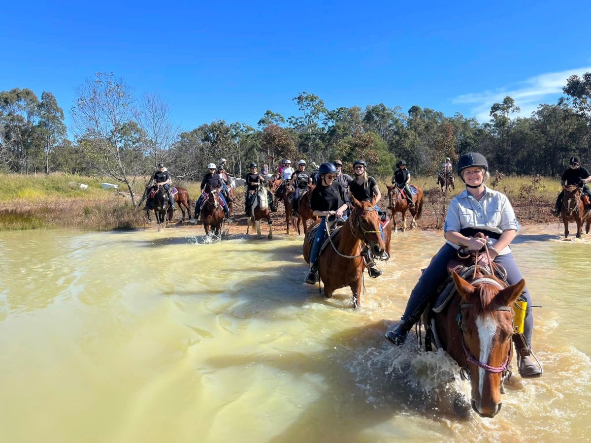 a group of people riding horses on a river