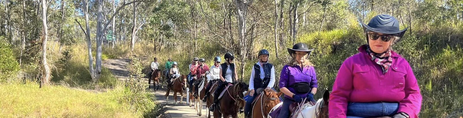 a group of people riding horses on a forest