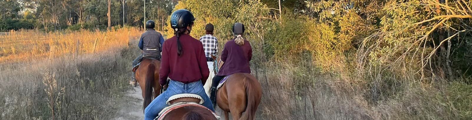 a group of people riding horses on a dirt road