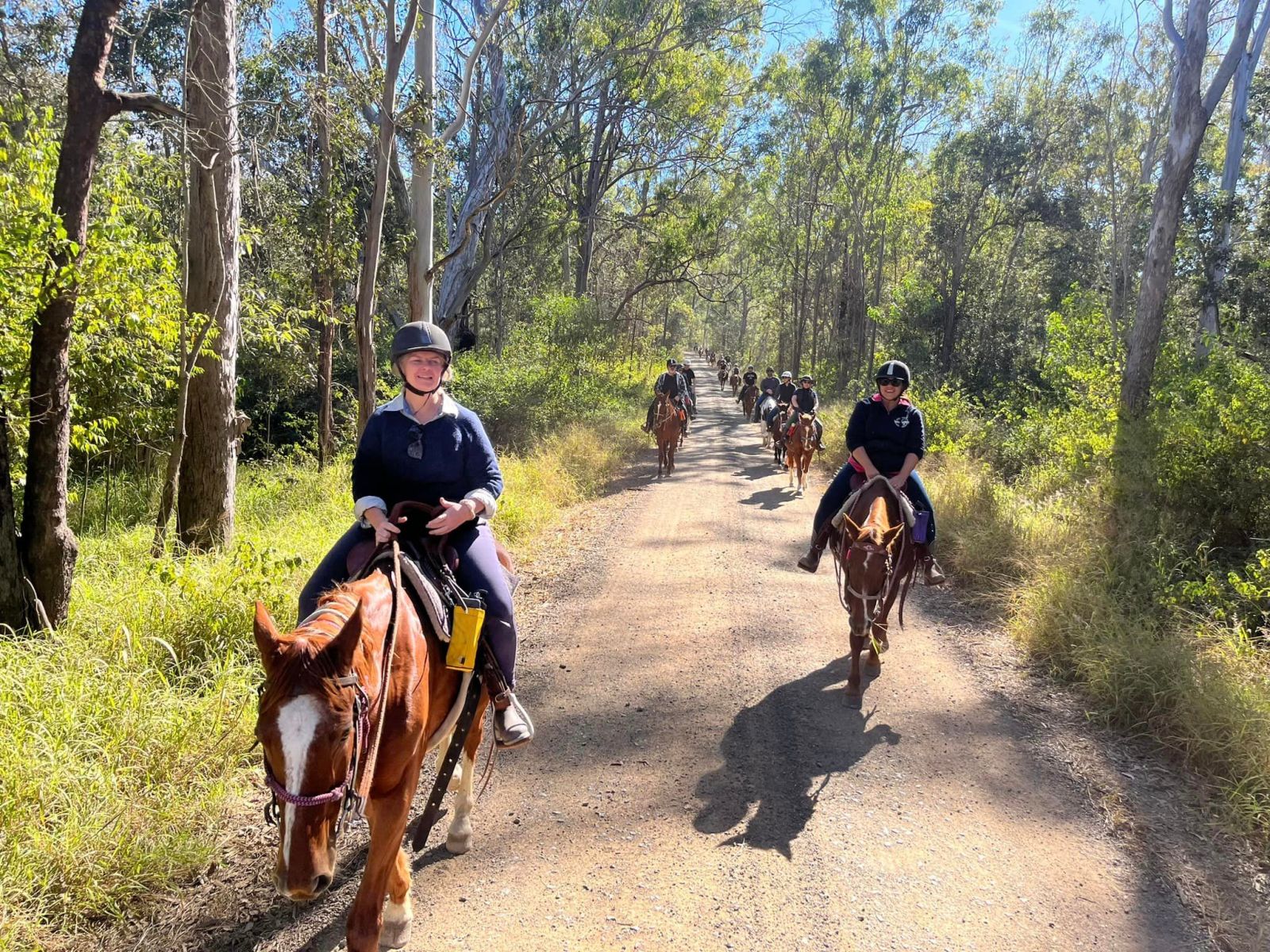 a group of people riding horses on a dirt road