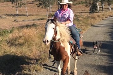 a woman riding a horse on a dirt road
