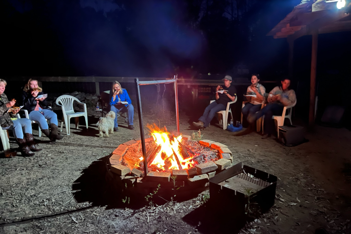 a group of people sitting around a campfire on a cowgirl camp