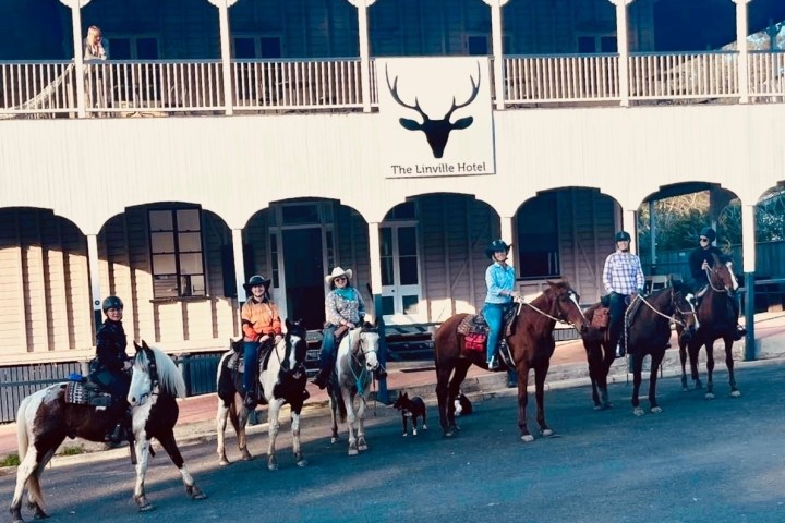 a group of people on horses posing for the camera in front of a building