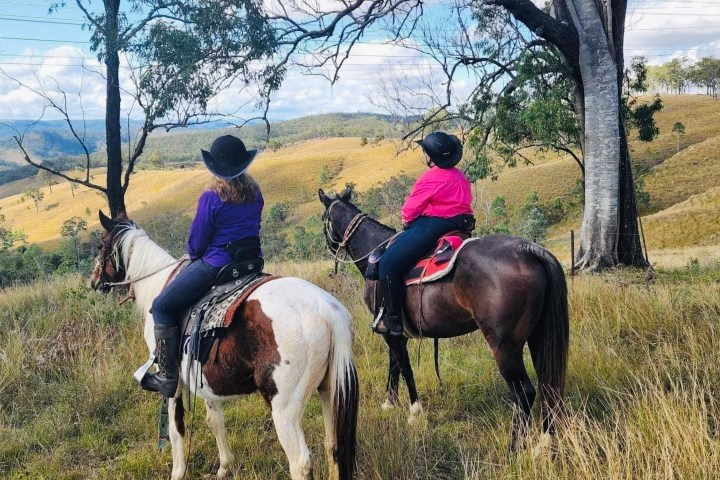 two women on horses looking out onto the field