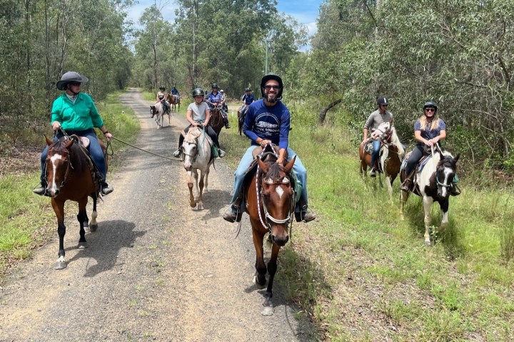 a group of people riding horses on a dirt road