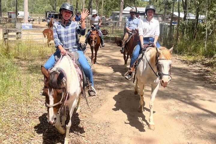 a group of people riding horses on a dirt road