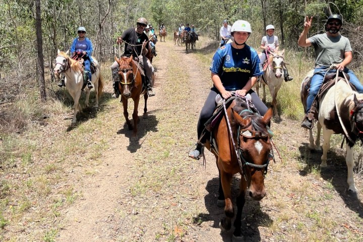 a group of people riding horses on a dirt road