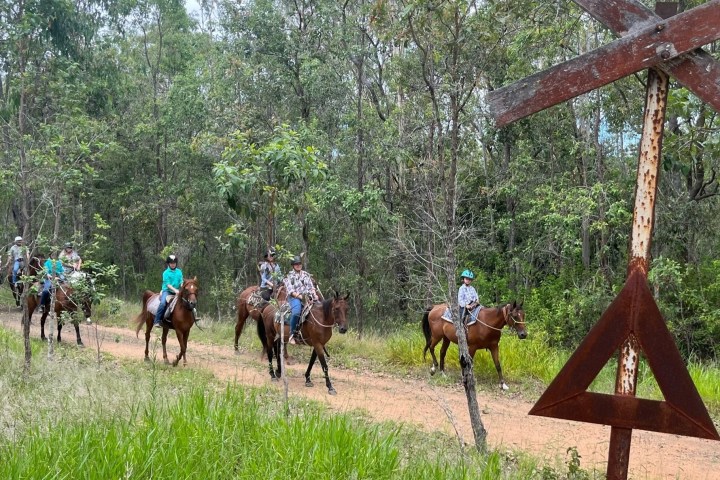 a group of people riding horses on a dirt road