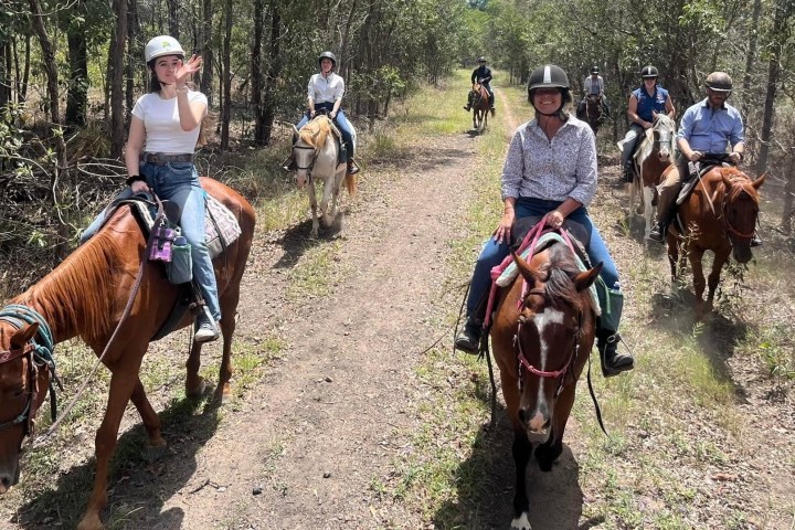 a group of people riding horses on a dirt road
